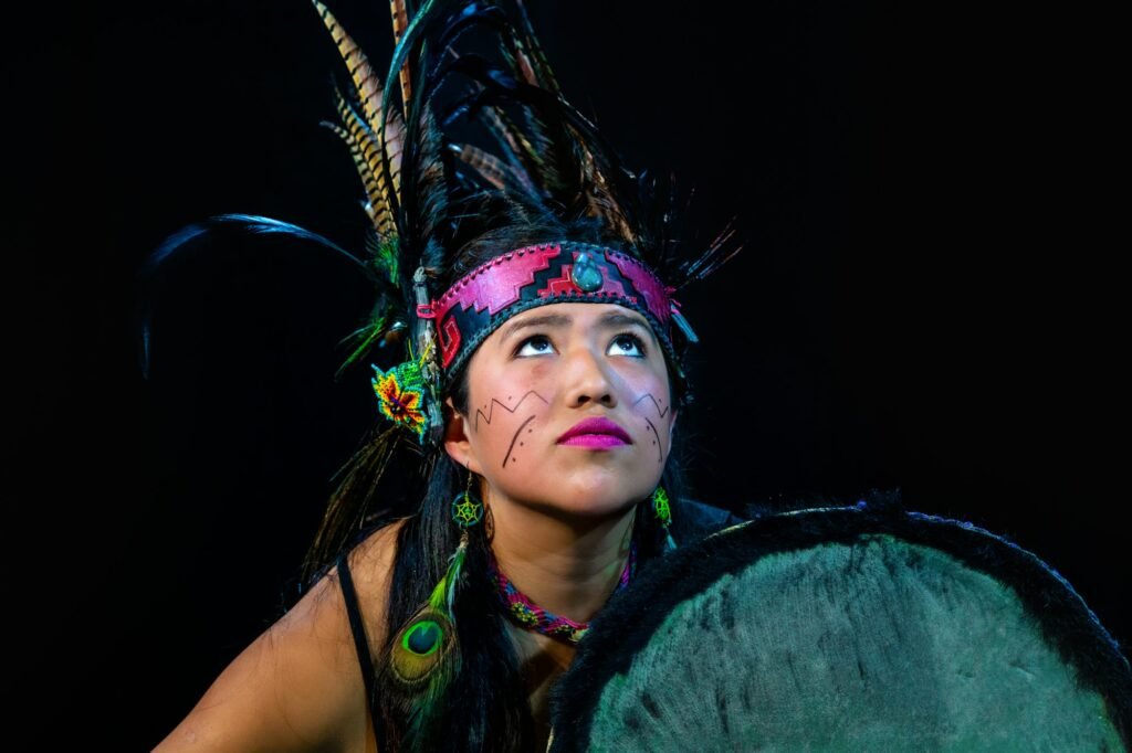 Young female with traditional dress dancing with trappings with feathers and drum