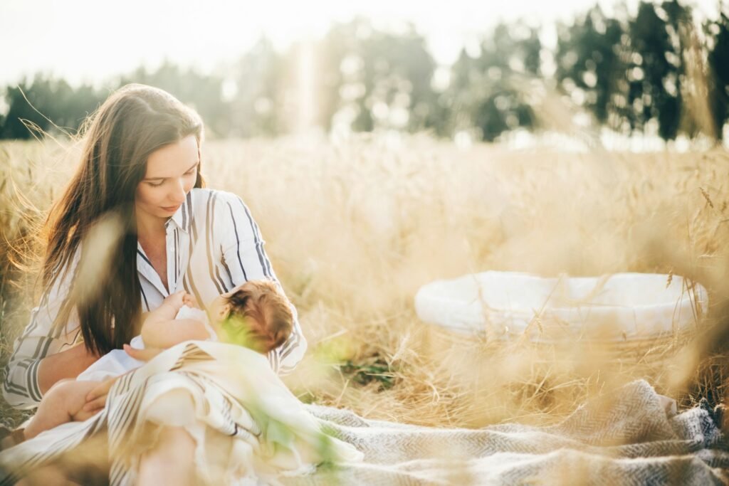 Little baby girl breastfeeding in nature meadow at the sunset .