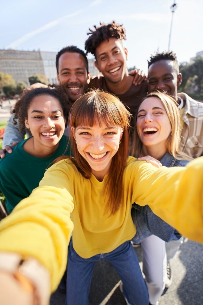 Vertical. Group of happy friends posing for a selfie on a spring day as they party together outdoors