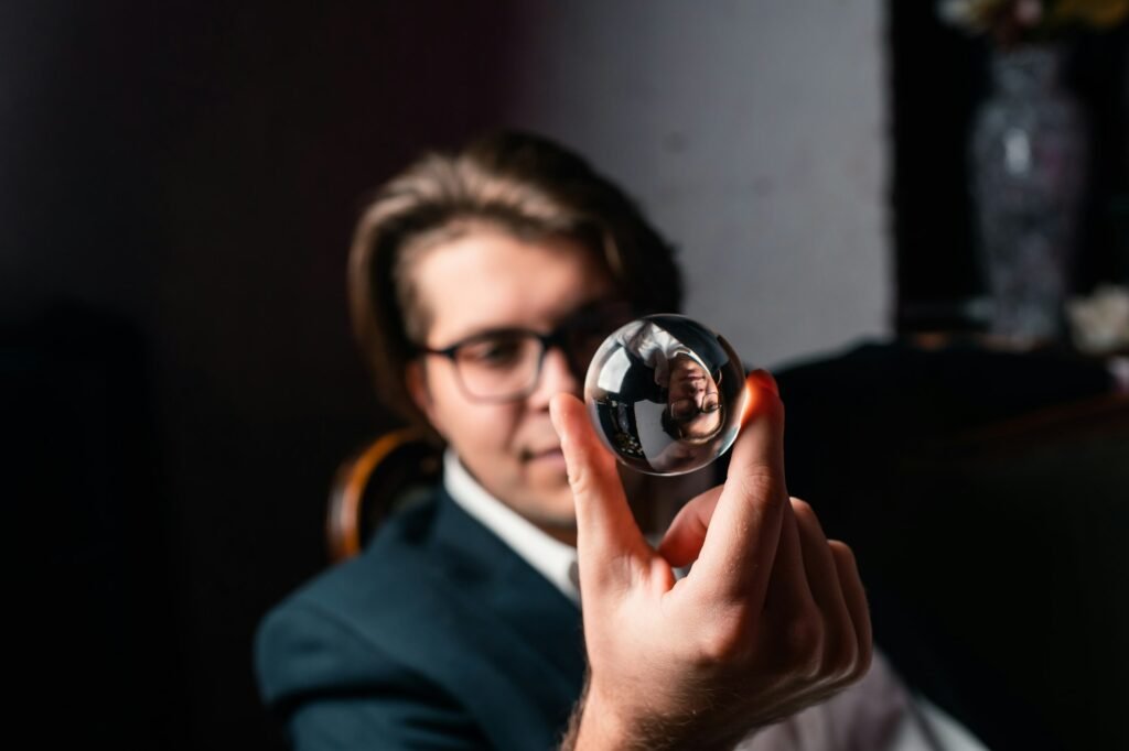 Young man holding a clear transparent crystal glass ball in their hand