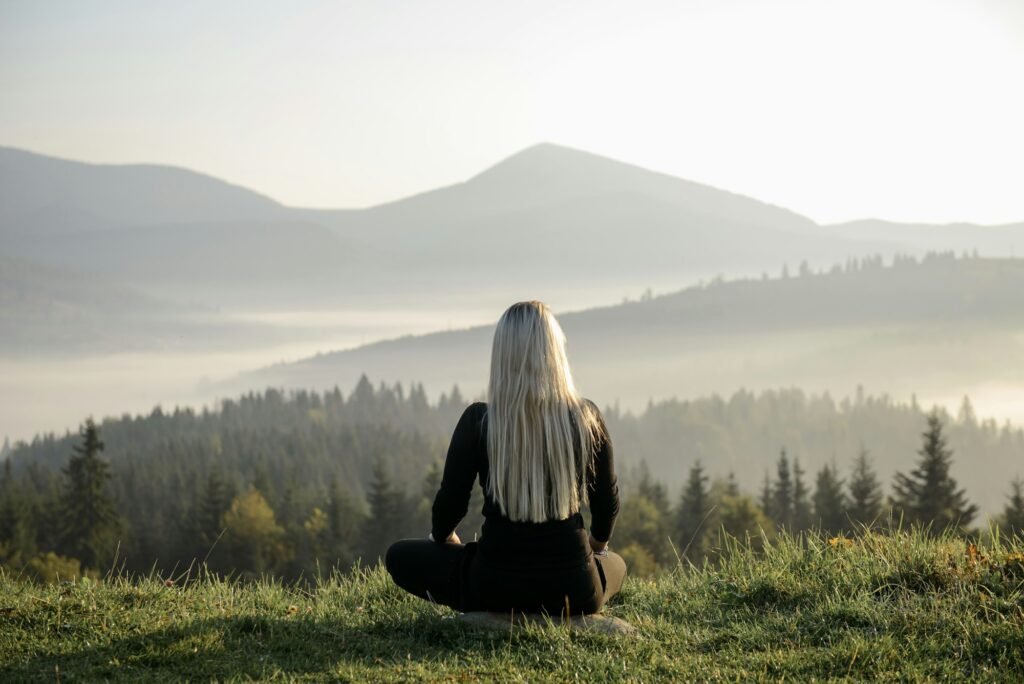 a girl with flowing hair sits in the mountains at dawn and meditates, does yoga