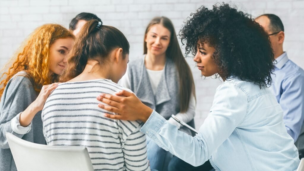 Addicted people comforting woman at psychotherapy session