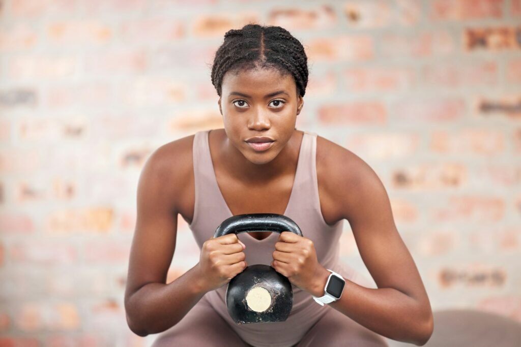 Black woman, face and kettlebell in gym workout, training or exercise for body muscle growth, cardi