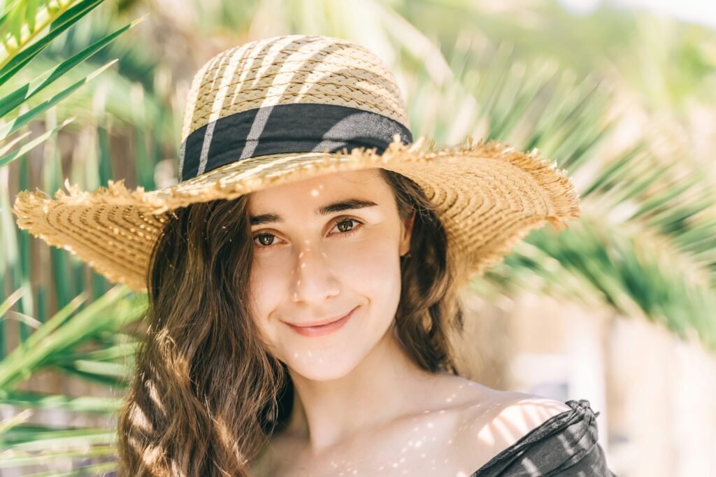 Jewish woman in straw hat near palm leaves.