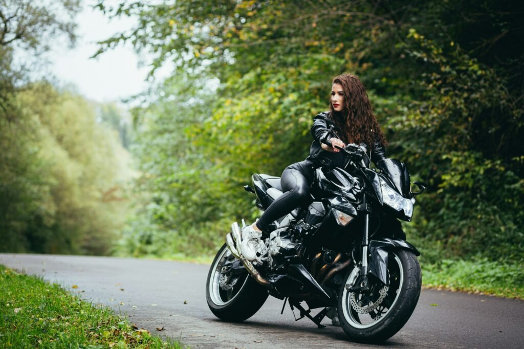 Portrait of a beautiful young woman sitting on a motorcycle, riding a motorcycle in black leather