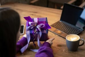 Purple gift box in a woman's hands in a purple sweater.