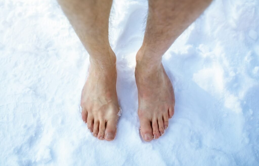 Top view of male feet standing on snow outdoors, cropped. Unrecognizable guy making cold exposure