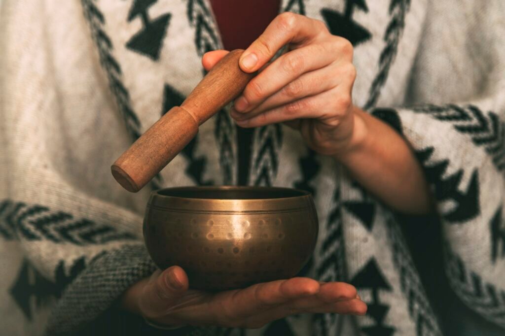 woman hands using tibetan bowl in meditation dressed with handmade poncho.