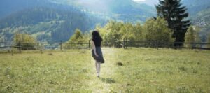 Woman in black dress barefoot is walking on the grass